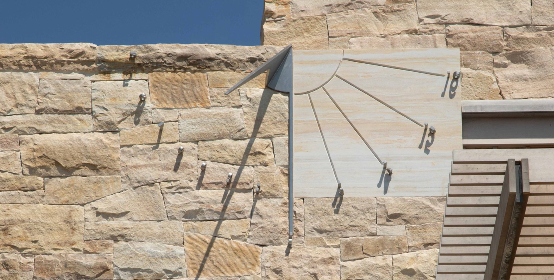 Image of sundial on stone wall.